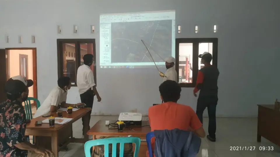 Pemaparan peta desa di layar proyektor kepada perangkat Desa Serang